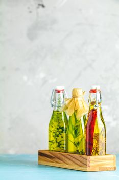 Different sorts of cooking oil. Assortment of sunflower, corn, olives oils with herbs and spices in different bottles on light concrete background
