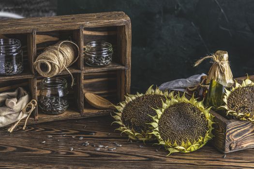 Organic sunflower oil in a small glass jars with sunflower seeds. Closeup photo of sunflower oil with seeds on wooden background. Bio and organic product concept.