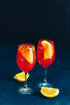 Two Aperol spritz cocktail in big wine glass with oranges, summer Italian fresh alcohol cold drink. Dark bar counter background with tools, summer mood concept, selective focus