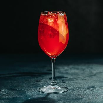 Cocktail aperol spritz on dark background.. Sunlight. Summer alcohol cocktail with orange slices. Italian cocktail aperol spritz on slate board. Trendy beverage	