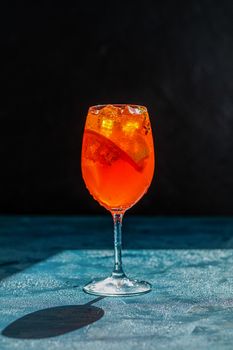 Cocktail aperol spritz on dark background.. Sunlight. Summer alcohol cocktail with orange slices. Italian cocktail aperol spritz on slate board. Trendy beverage. Color of 2020 year. Classic Blue.