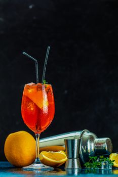 Cocktail aperol spritz in big wine glass with water drops on dark background. Summer alcohol cocktail with orange slices. Italian cocktail aperol spritz on slate board. Trendy beverage