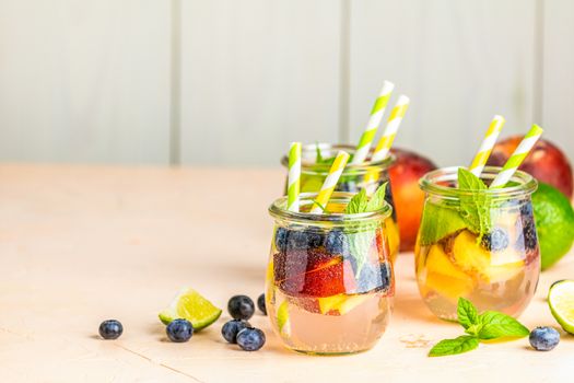 Blueberry and peach infused water, cocktail, lemonade or tea. Summer iced cold drink with blueberry, lime, peach and mint. Selective focus.