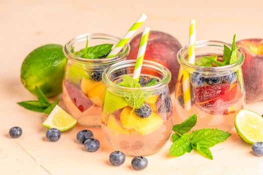 Blueberry and peach infused water, cocktail, lemonade or tea. Summer iced cold drink with blueberry, lime, peach and mint. Selective focus.