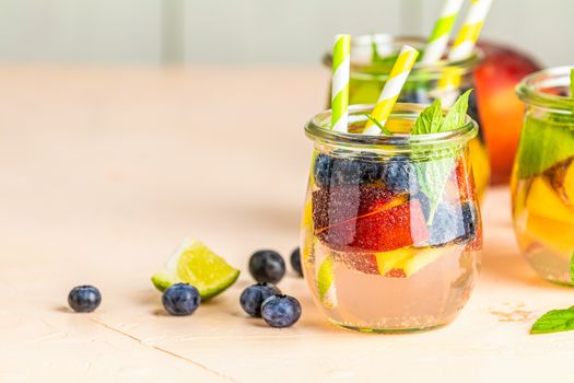 Blueberry and peach infused water, cocktail, lemonade or tea. Summer iced cold drink with blueberry, lime, peach and mint. Selective focus.