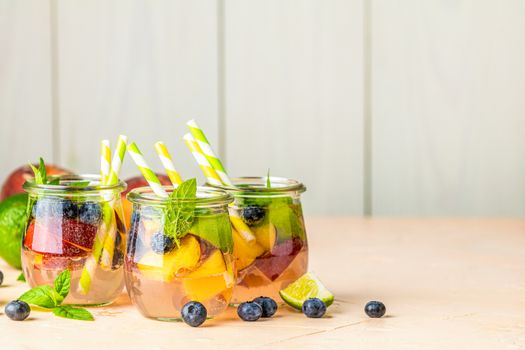 Blueberry and peach infused water, cocktail, lemonade or tea. Summer iced cold drink with blueberry, lime, peach and mint. Selective focus.
