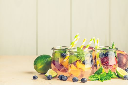 Blueberry and peach infused water, cocktail, lemonade or tea in jar with water drops. Summer iced cold drink with blueberry, lime, peach and mint