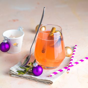 Christmas and New Year pink cocktail with fig and cinnamon  in glass on pink concrete background, close up, surrounded  holiday decor. Winter festive drinks and alcoholic cocktails or detox drink