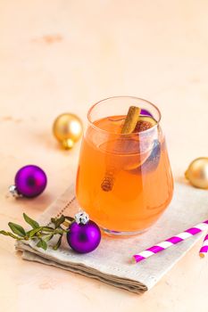 Christmas and New Year pink cocktail with fig and cinnamon  in glass on pink concrete background, close up, surrounded  holiday decor. Winter festive drinks and alcoholic cocktails or detox drink