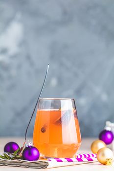 Christmas and New Year pink cocktail with fig and cinnamon  in glass on pink concrete background, close up, surrounded  holiday decor. Winter festive drinks and alcoholic cocktails or detox drink