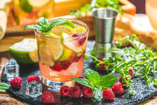 Refreshing mint cocktail mojito with rum, lime and raspberry, cold drink or beverage