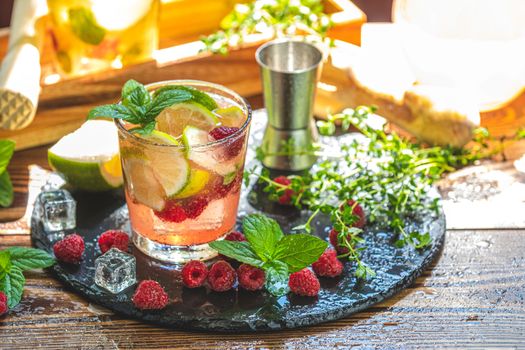 Refreshing mint cocktail mojito with rum, lime and raspberry, cold drink or beverage. Close up