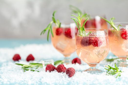 Christmas pink drink raspberry with rosemary and ice. Glasses with cold and healthy beverage. Welcome drink. Holiday