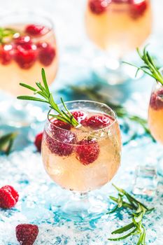 Christmas pink drink raspberry with rosemary and ice. Glasses with cold and healthy beverage. Welcome drink. Holiday, sunny light