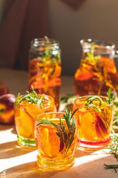 Glasses with drops of sweet peach iced tea, Summer cold peach fizz cocktail with rosemary. Sunny light. Shallow depth of the field, close up, copy space for you text