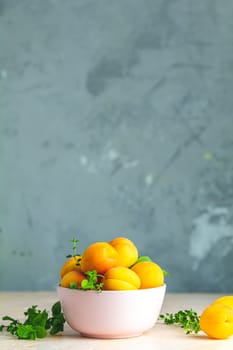 Fresh sweet orange apricots in pink bowl on the pink concrete surface table, selective focus, shallow depth of the fields