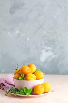 Fresh sweet orange apricots in pink bowl on the pink concrete surface table, selective focus, shallow depth of the fields