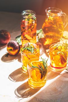 Glasses of sweet peach iced tea, Summer cold peach fizz cocktail with rosemary. Sunny light. Shallow depth of the field, close up, copy space for you text