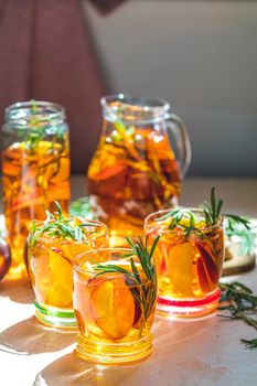 Summer cold peach fizz cocktail or iced tea with rosemary. Sunny light. Shallow depth of the field, close up, copy space for you text.