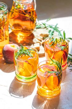 Glasses of sweet peach iced tea, Summer cold peach fizz cocktail with rosemary. Sunny light. Shallow depth of the field, close up, copy space for you text