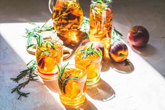 Glasses of sweet peach iced tea, Summer cold peach fizz cocktail with rosemary. Sunny light. Shallow depth of the field, close up, copy space for you text