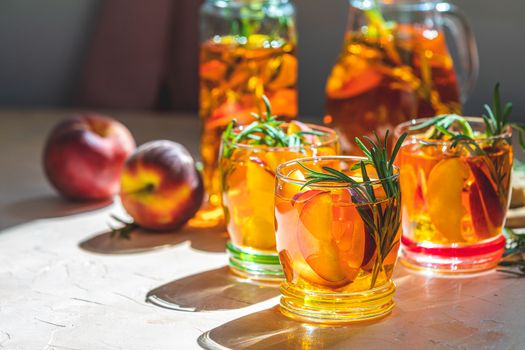 Summer cold peach fizz cocktail or iced tea with rosemary. Sunny light. Shallow depth of the field, close up, copy space for you text.