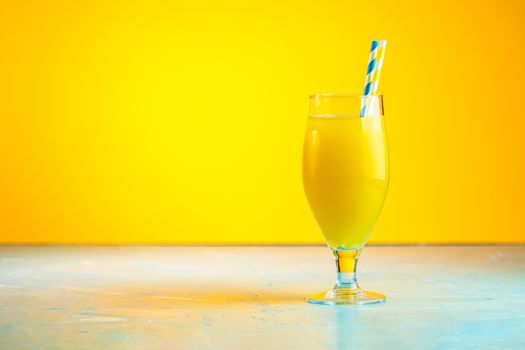 Glass of pineapple tropical fresh juice on yellow background. Summer drinks and alcoholic cocktails. 
