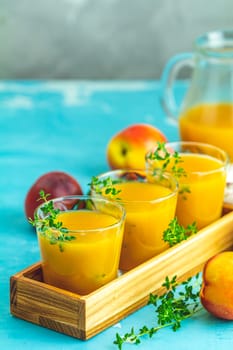 Glass of fresh healthy peach smoothie or juice in wooden box on light blue concrete surface table. Shallow depth of the field, close up, copy space for you text