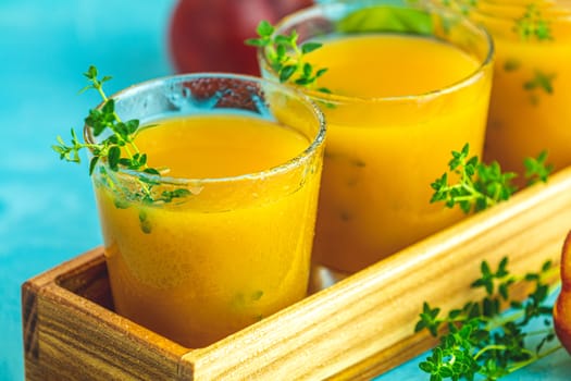 Glass of fresh healthy peach smoothie or juice in wooden box on light blue concrete surface table. Shallow depth of the field, close up, copy space for you text