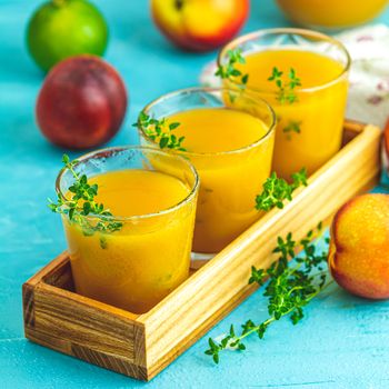 Glass of fresh healthy peach smoothie or juice in wooden box on light blue concrete surface table. Shallow depth of the field, close up, copy space for you text