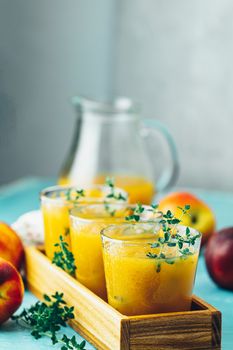 Glass of fresh healthy peach smoothie or juice in wooden box on light blue concrete surface table. Shallow depth of the field, close up, copy space for you text