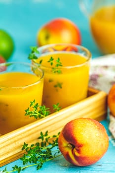 Glass of fresh healthy peach smoothie or juice in wooden box on light blue concrete surface table. Shallow depth of the field, close up, copy space for you text.