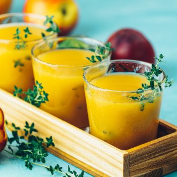 Glass of fresh healthy peach smoothie or juice in wooden box on light blue concrete surface table. Shallow depth of the field, close up, copy space for you text