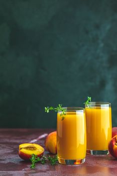 Glass of fresh healthy peach smoothie or juice on dark concrete surface table. Shallow depth of the field, close up, copy space for you text