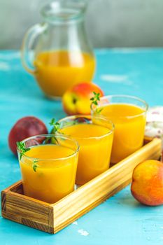 Glass of fresh healthy peach smoothie or juice in wooden box on light blue concrete surface table. Shallow depth of the field, close up, copy space for you text