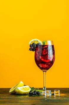 Cold red cocktail with blackcurrant, lemon, mint and ice in tall glass on yellow background. Summer drinks and alcoholic cocktails. Alcoholic cocktail Blackcurrant mojito