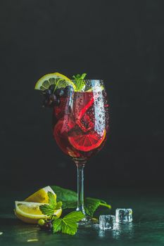 Cold red cocktail with blackcurrant, lemon, mint and ice in tall glass on black background. Summer drinks and alcoholic cocktails. Alcoholic cocktail Blackcurrant mojito