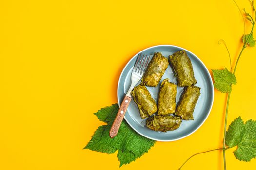 Traditional Middle Eastern dolma or tolma. Latin American Mexican Chilean cuisine ninos envueltos. Grape leaves stuffed with meat and rice. Yellow surface