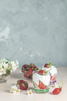 Cream strawberry. Glass bowl of strawberries with whipped cream and mint. Jasmine flowers. Concrete surface, copy space for you text.