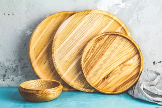 Variety of wooden bowl, wooden spoons for salad over blue texture background. Food or ecology kitchen concept. Copy space for you text.