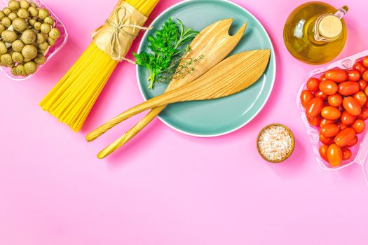 Spaghetti, shimeji mushroom, olive oil,  pink salt, empty ceramic bowl, wooden spoons for salad over pink background. Top view, flat lay, healthy food concept, copy space for you text.