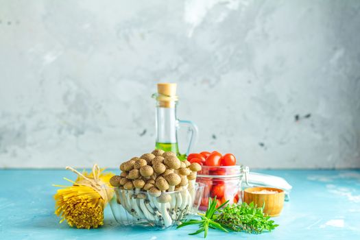 Spaghetti, shimeji mushroom, olive oil,  pink salt, empty ceramic bowl, wooden spoons for salad over blue concrete background. Healthy food concept, copy space for you text.