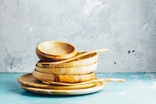 Variety of wooden bowl, wooden spoons for salad over blue texture background. Food or ecology kitchen concept. Copy space for you text.