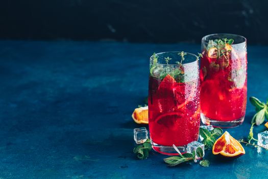 Cocktail bloody orange margarita in highball glass. Refreshing summer drinks. Cocktail blood orange margarita, in glasses on a dark blue concrete table surface with a garnish of orange. Copy space.