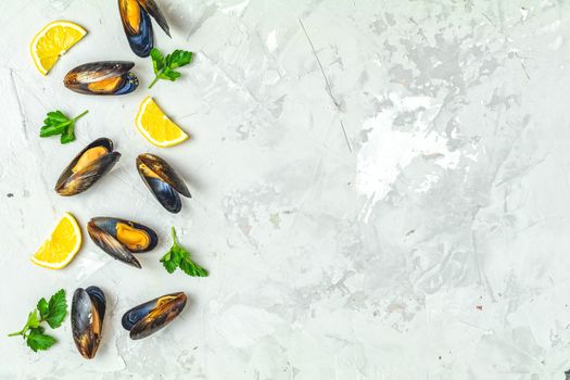 Seafood mussels with lemon and parsley on light gray concrete table surface, top view, copy space for you text. Food background