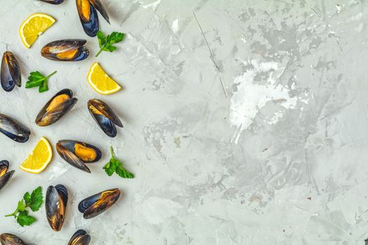 Seafood mussels with lemon and parsley on light gray concrete table surface, top view, copy space for you text