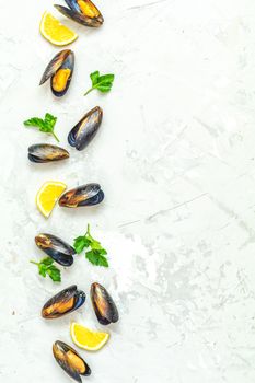 Seafood mussels with lemon and parsley on light gray concrete table surface, top view, copy space for you text. Food background