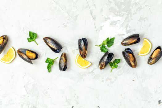 Seafood mussels with lemon and parsley on light gray concrete table surface, top view, copy space for you text. Food background