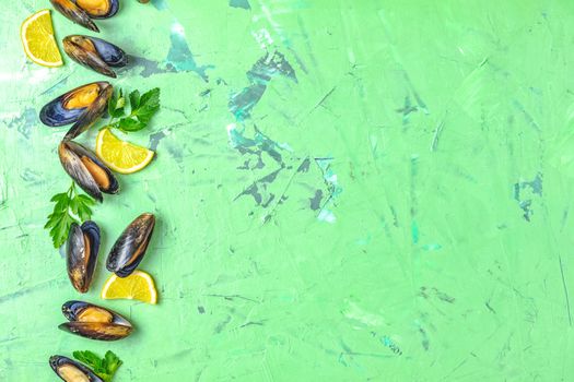 Seafood mussels with lemon and parsley on green concrete table surface, top view, copy space for you text