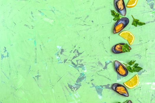 Seafood mussels with lemon and parsley on green concrete table surface, top view, copy space for you text